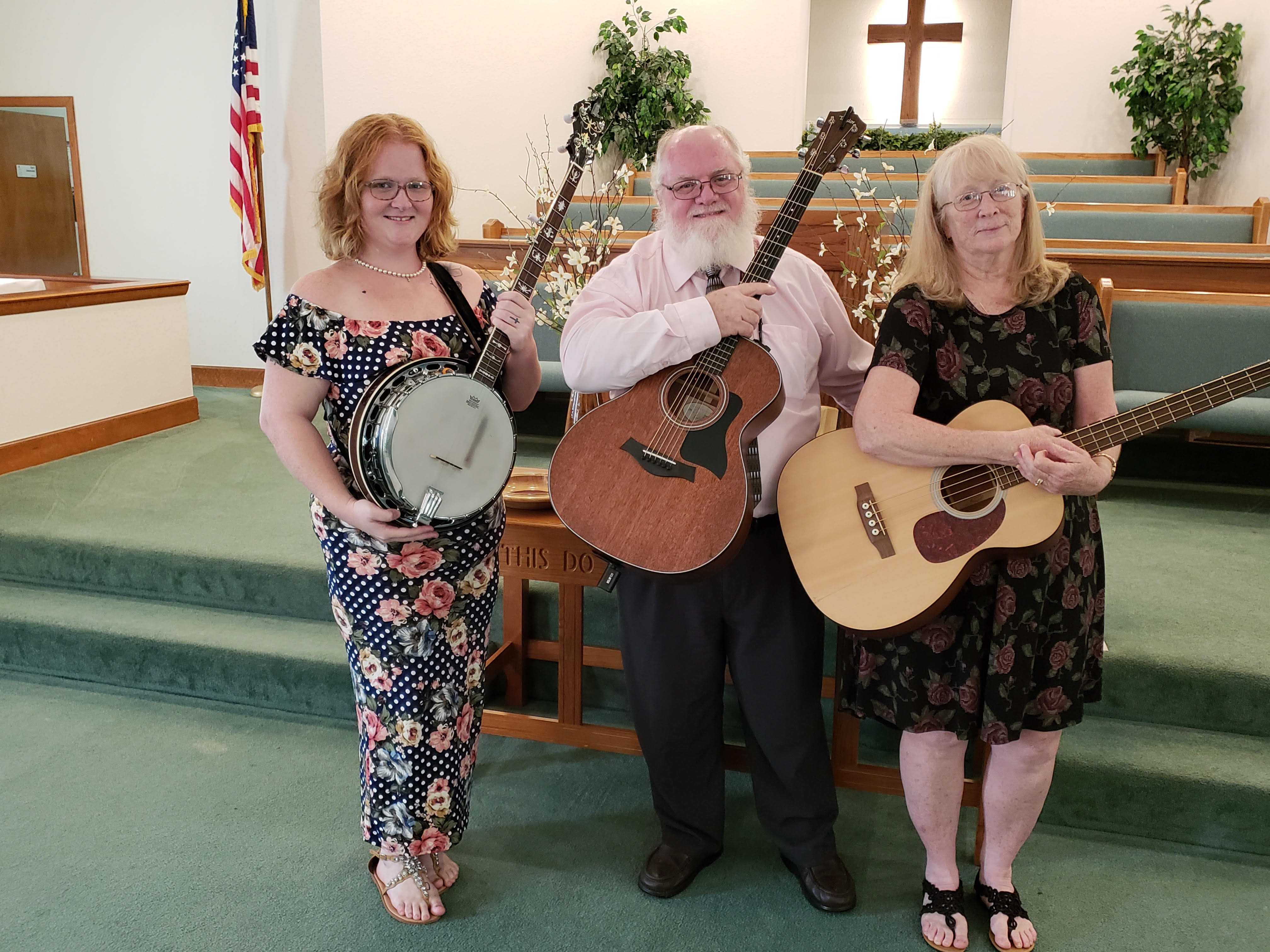 Muscial worship leaders,one holding his acoustic guitar,one holding her acoustic bass,one holding her banjo